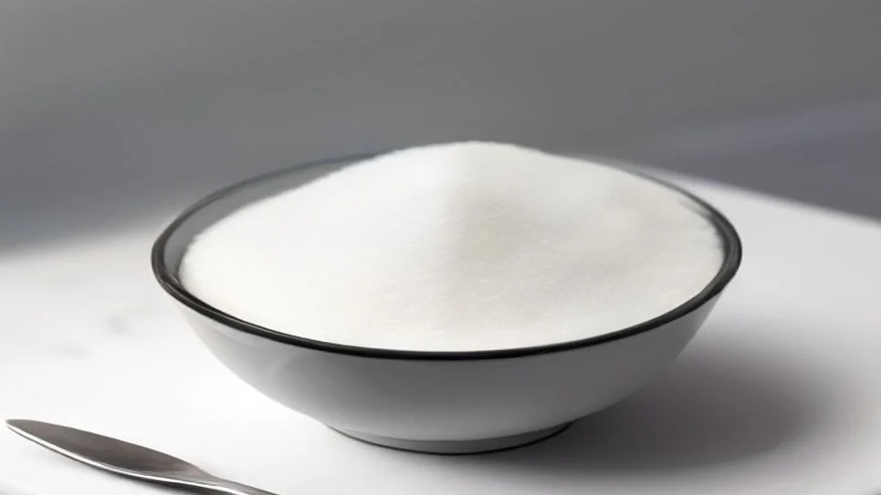 a small white bowl filled with granulated white sugar on a countertop